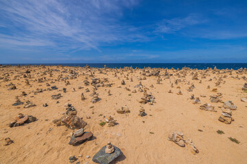 Beautiful view of coast of Atlantic ocean of island of Aruba with small cairns lined.