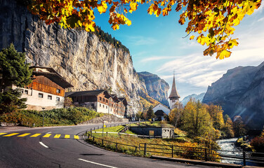 Naklejka premium Picturesque autumn landscape. Panoramic view of stunning mountain scenery in the Alps with fresh green meadows with fog in mountains on a sunny morning in autumn. Lauterbrunnen, Switzerland.