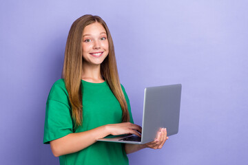 Photo of positive pretty schoolkid pupil hold use netbook do homework empty space isolated on purple color background