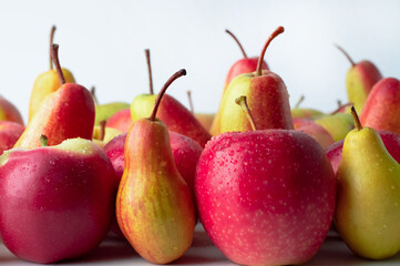 Blurred image of red apples and pears on a light background.