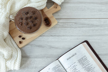 Habakkuk open holy bible book with coffee cup and cozy woolen scarf. Top table view. Winter and autumn composition. Morning study, Christian Old Testament prophecy. Biblical concept.	