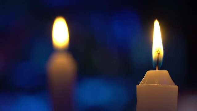 Velas acesas com fundo azul desfocado, com luzes formando desenhos abstratos em movimento, projetados sobre este fundo