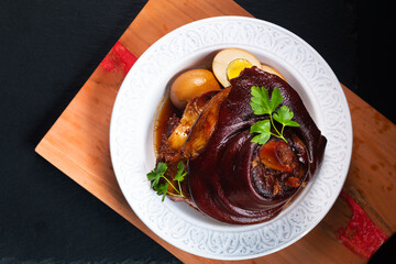Asian food concept Chinese 5 Spice Braised Pork Knuckle on wooden board on black slate stone background with copy space