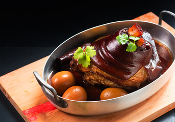 Asian food concept Chinese 5 Spice Braised Pork Knuckle on wooden board on black slate stone background with copy space