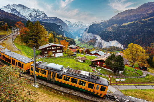 Wonderful Sunny landscape. tourist train traveling on the railway thru Wengen village by green grassy hillside. Concept of an ideal resting place. Creative image. retro style