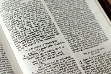 Message to Philadelphia, biblical verses in open bible book of Revelation. A closeup. Christian biblical concept.