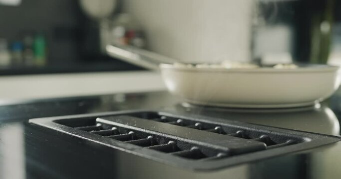 Potatoes are fried on a modern induction cooker. Built-in extractor works. Side view