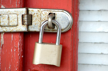 Close up of gold padlock on red door.