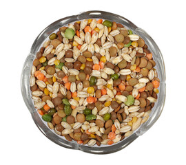 Mixed uncooked legumes and cereals, peeled barley, green, yellow and dark red lentils, half green peas, black white beans, green beans in glass bowl, top view