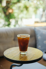 Iced Americano coffee glass on wooden indoor cafe table