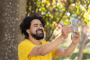 portrait of a Mexican man smiling with afro and beard taking selfie