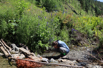 A teenage girl drinks from a stream while walking