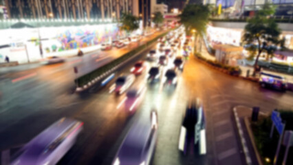 blurred picture of many cars speed lights at the intersection of siam square, Bangkok, Thailand at night. defocused of cars moving on the road. MBK center busy traffic at night.