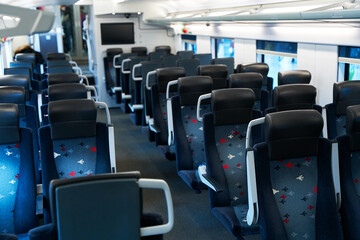 The deserted interior of a high-speed train. Rows of empty seats