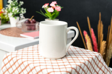 Obraz na płótnie Canvas A white blank coffee mug on the top of a hand cloth with simple decorations arranged around it