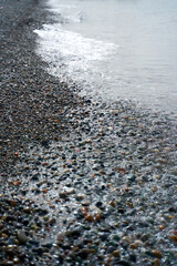 Stone pebbles on the beach of the black sea. Water washes ashore