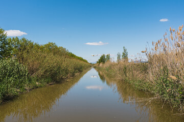 Commercial airplane flying just above a wide green river.