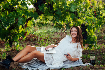 woman sitting by a grape with a glass of red wine