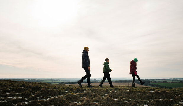 Family of 3 walking along a hill top in Winter