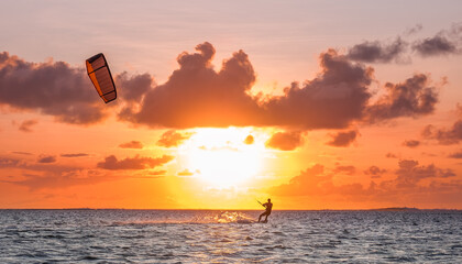 Sunset sky over the Indian Ocean bay with a kiteboarder riding kiteboard with a green bright power kite. Active sport people and beauty in Nature concept image. Le Morne beach, Mauritius