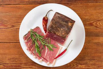 Partly sliced dry-cured pork belly with rosemary and chili