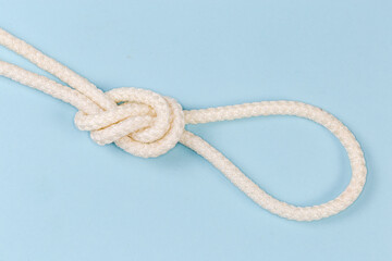 Rope knot as overhand loop on blue background close-up