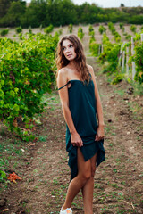Fototapeta premium woman from the village in a green dress stands in a vineyard