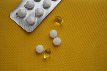 White pills on a yellow background. Blister with tablets. A place for writing. Background with medicines. Vitamins on a yellow background. Antibiotics