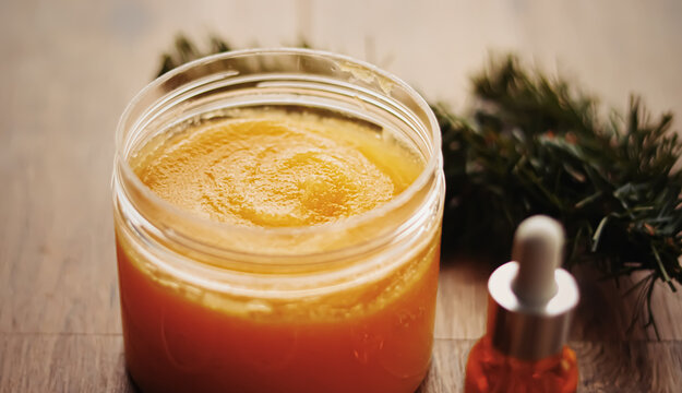 Citrus and honey orange body scrub jar on rustic wood background, beauty cosmetic and skincare product.
