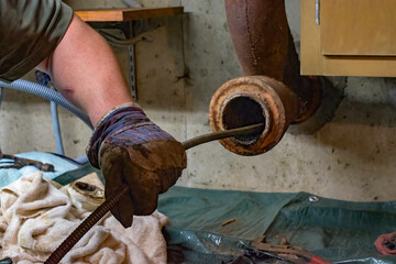 Hands of a plumber as he runs a camera scope and cleaning machine through the main pipe to unclog the drain to the Septic System. Hard-working tradesman. - obrazy, fototapety, plakaty