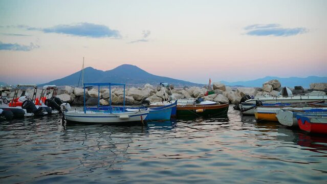 Naples, Italy - 12.06.2022: Fishing boats and Vesuvius mountain.