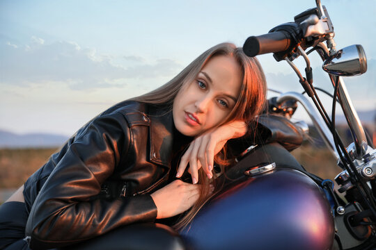 Beautiful young woman on motorcycle outdoors in evening