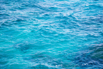 Water background, turquoise shallow sea water. Beautiful texture of sun glare on the water.
