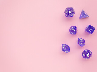 Violet rpg dice on a pink background with space for text