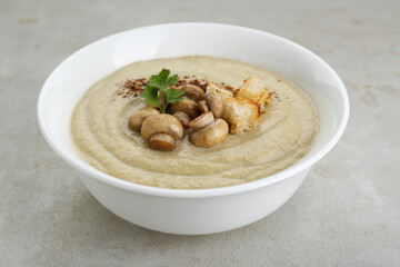 Delicious cream soup with mushrooms and croutons on beige textured table, closeup