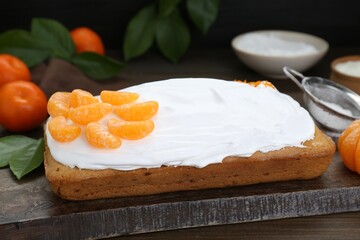 Delicious homemade yogurt cake with tangerines and cream on wooden table, closeup