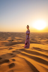 A woman dressed like a princess in a desert during sunset. Dubai, UAE.