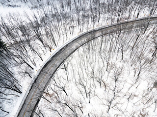 Aerial drone view of a bend in a rural road in a snowy forest in Wisconsin