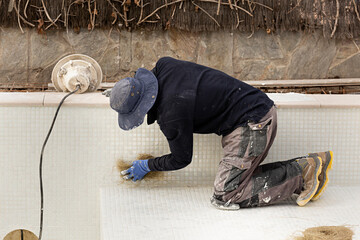 Obrero poniendo mosaico de gresite en piscina.