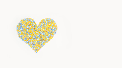 Pills of yellow and blue color in the form of a heart on a white background. Medicine, treatment, pharmacology, health. Top view Space for text