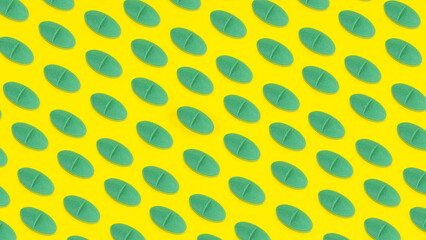 Yellow medicine background with green pills and tablet, macro. Drug production backdrop. Medical pattern from vitamin capsule, closeup