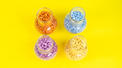 Colorful assorted pharmaceutical medicine pills, tablets and capsules and bottle on yellow background. Capsules Vitamin And Dietary Supplements