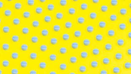 Yellow medicine background with blue pills and tablet, macro. Drug production backdrop. Medical pattern from vitamin capsule, closeup