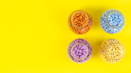 Colorful assorted pharmaceutical medicine pills, tablets and capsules and bottle on yellow background .Capsules Vitamin And Dietary Supplements Space for text on the left