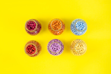 Colorful assorted pharmaceutical medicine pills, tablets and capsules and bottle on yellow background. Capsules Vitamin And Dietary Supplements Close up view from above