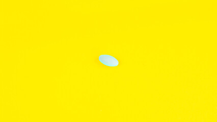 Pill of white color on a yellow background. Medicine, treatment, pharmacology, health, concept. Top view Space for text