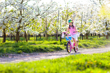 Kids on bike in spring park. Girl riding bicycle.