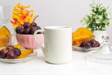 A white blank coffee mug on the top of a rounded mat with the fresh fruits arranged around it