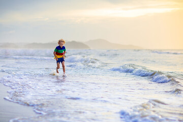 Child playing on ocean beach. Kid at sunset sea.