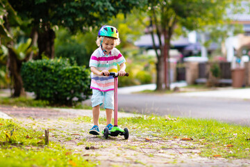 Little boy riding scooter. Kids ride kick board.